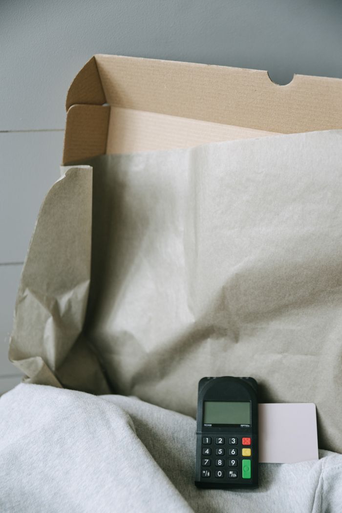 Image of a payment terminal with a cardboard box and paper, representing online shopping and contactless payment.